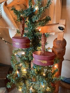 a small christmas tree decorated with wooden buckets and lights in the shape of crosses