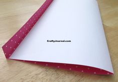 an open white paper with pink polka dots on it sitting on a wooden table top