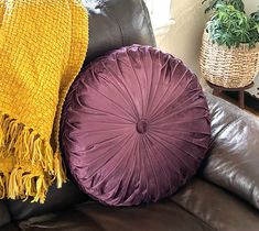 three pillows are sitting on the back of a leather couch in front of a window