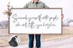 a woman holding up a sign that says, surround yourself before people who lift you higher