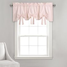 a white chair sitting in front of a window with pink bow valances on it