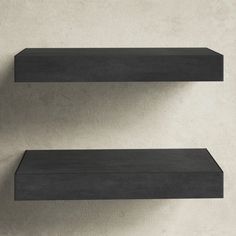 two black shelves on the wall with one empty shelf