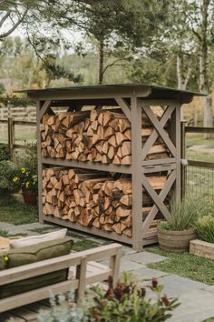 a large stack of logs sitting on top of a lush green field next to a wooden bench