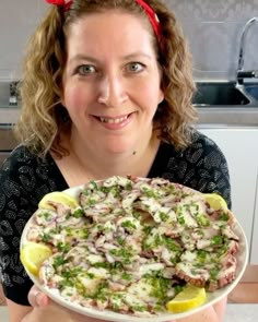 a woman is holding a dish with broccoli and other food items on it