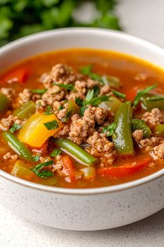 a white bowl filled with meat and vegetable soup on top of a table next to some parsley