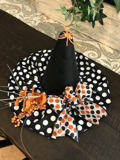 a black hat with polka dots and orange bows on it sitting on top of a table