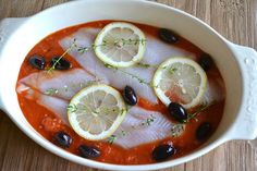 fish with olives and lemon slices in a bowl