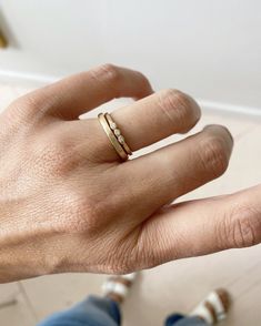 a person's hand with a gold ring on their left thumb and two other fingers