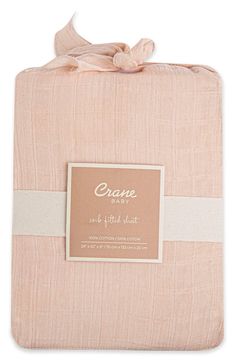 the creme baby blanket in pink is folded and has a label on it that says,