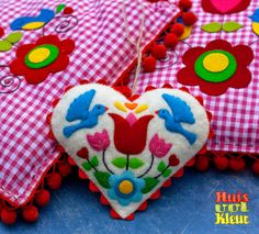 two red and white heart shaped pillows on top of a blue table cloth covered with pom poms