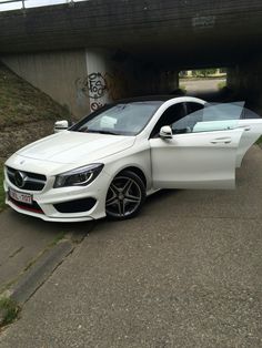 a white mercedes cla parked under a bridge