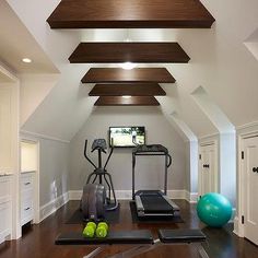 an exercise room with treadmills, yoga mat and green balls on the floor