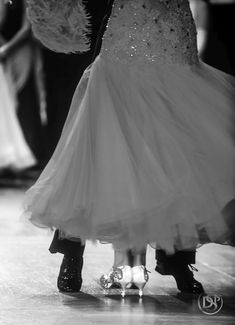 two people dressed in formal wear dancing on a dance floor with their feet covered by feathers