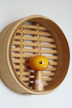 a wooden toy in a round holder on a white wall with an orange cat figurine