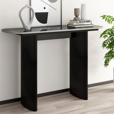 a black console table with a white vase on top and a plant next to it