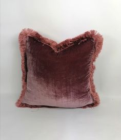 a purple and pink velvet pillow on a white background with fluffy fur trimmings