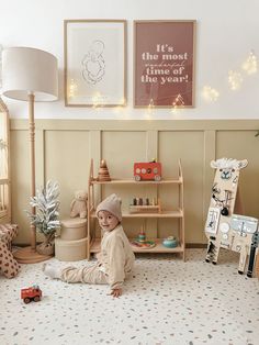 a young child sitting on the floor in front of a shelf with toys and books