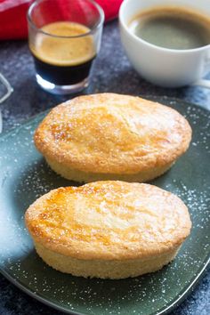 two biscuits on a plate next to cups of coffee