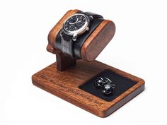 a watch on a wooden stand with two cufflinks in front of the watch