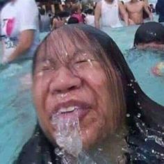 an old woman is in the water with her mouth open and people around her looking on