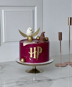 a purple cake with gold decorations and a white bird sitting on top of the cake