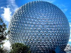 a large ball shaped building in the middle of a park with trees and bushes around it