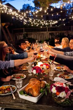 a group of people sitting around a wooden table with food and wine glasses on it