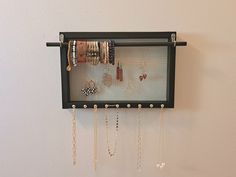 a wall mounted jewelry rack with many different bracelets and necklaces hanging on it