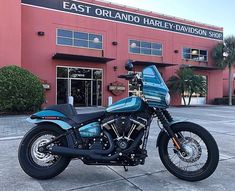 a blue motorcycle parked in front of a building with palm trees on the side walk