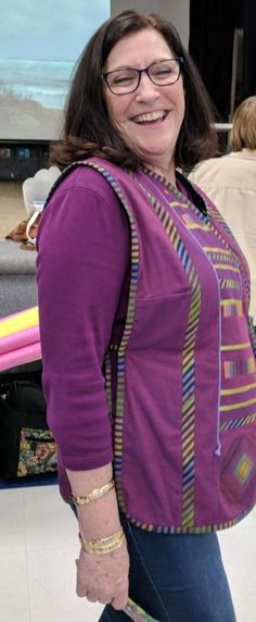 a woman with glasses and a purple shirt is holding a skateboard in her hand