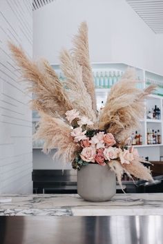 a vase filled with lots of flowers on top of a counter