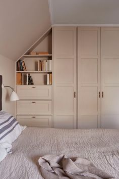 a white bed sitting in a bedroom next to a book shelf