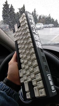 a person is holding a computer keyboard in their hand while driving through the snow covered street