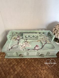 a green tray with birds painted on it next to a potted plant and vase