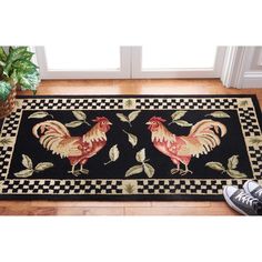 a rug with two roosters on it next to a potted plant in front of a window