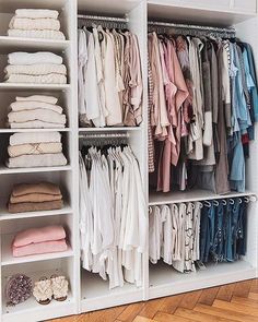 an organized closet filled with clothes and folded linens on shelving unit shelves in front of hardwood flooring