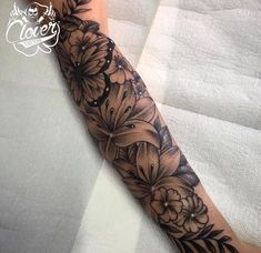 a woman's arm with black and white flowers on the inside of her forearm