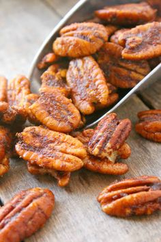 some pecans are sitting on a wooden table next to a metal scoop full of them