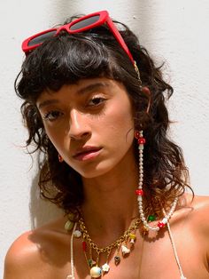 a woman with sunglasses on her head wearing beads and necklaces