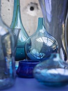 blue glass vases are sitting on a table with other glassware around the edges