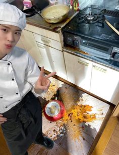 a young boy wearing a chef's outfit and pointing to the side while standing in front of an oven