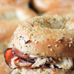 a close up of a bagel sandwich with meat and cheese on it's bun