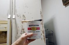 a person holding a can of rustoleum in front of a dirty refrigerator door