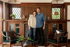 a man and woman standing in front of a fireplace