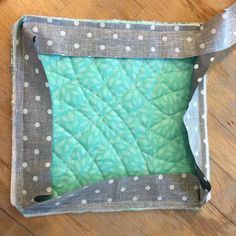 a green and white quilted square with polka dots on the edges, sitting on a wooden floor