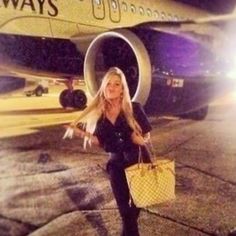 a woman is standing in front of an airplane with her hand on her hip and holding a yellow purse