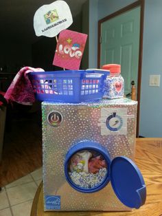 a toy washing machine sitting on top of a wooden table next to a blue basket