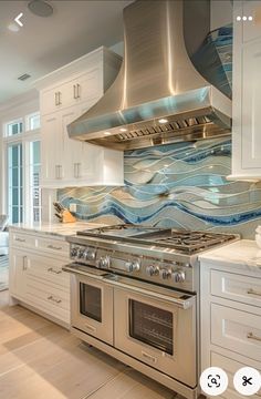 a kitchen with white cabinets and stainless steel stove top oven in the middle of it