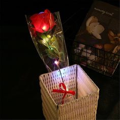 a white basket with flowers in it and a red ribbon tied to the handle, sitting on a table