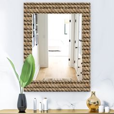 a mirror that is on the side of a wall next to a vase with a plant in it